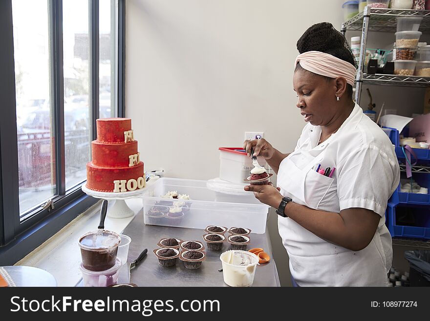 Young black woman frosting cakes at a bakery
