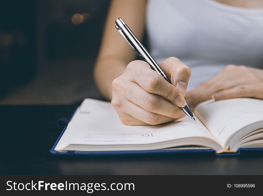 Photo of Person Writing on Notebook