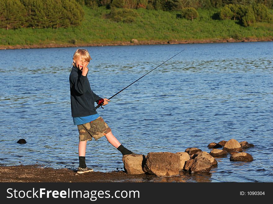 A boy fishing in a trout lake in northern europe. A boy fishing in a trout lake in northern europe