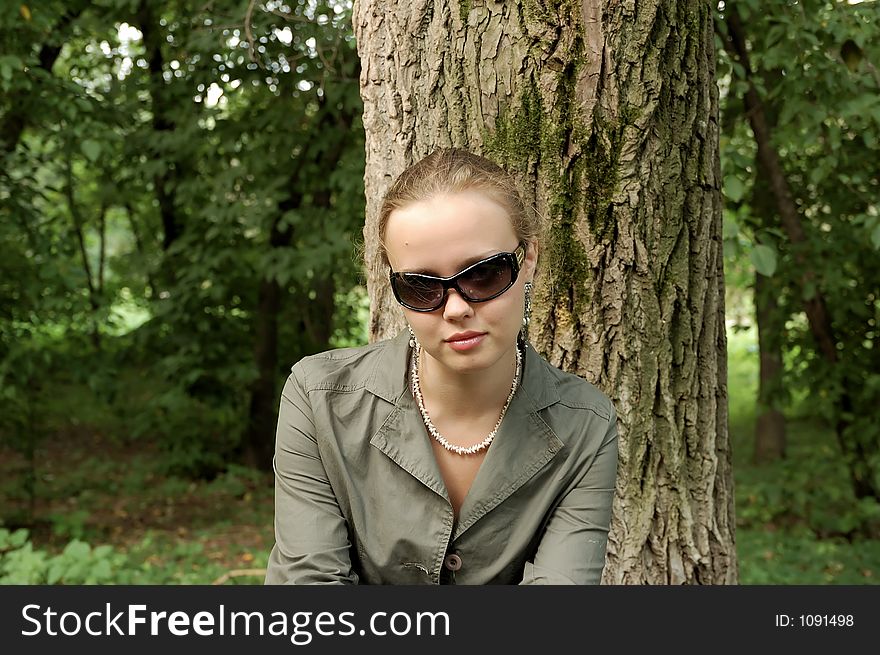 Beautiful girl sitting on a park with sun glasses, sunshade