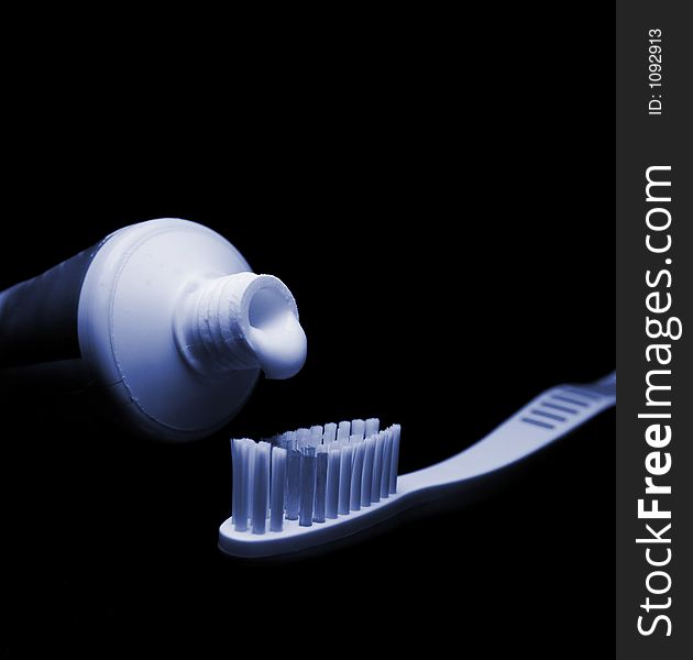 Toothbrush and toothpaste isolated on black. Tinted blue to suggest night time. Toothbrush and toothpaste isolated on black. Tinted blue to suggest night time.