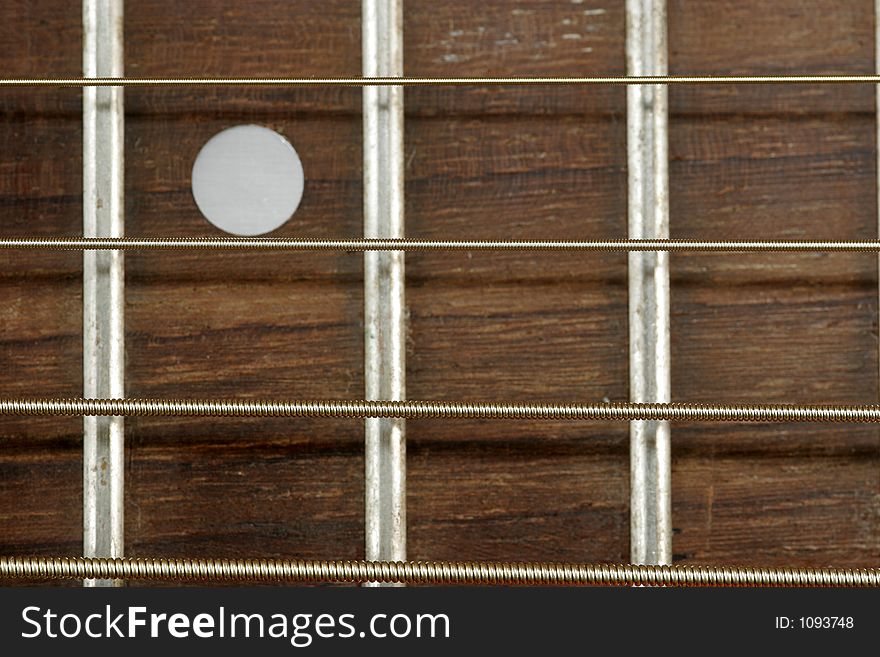 Close up of fret board. Fret marker included in composition. Narrow depth of field with strings in focus. Close up of fret board. Fret marker included in composition. Narrow depth of field with strings in focus