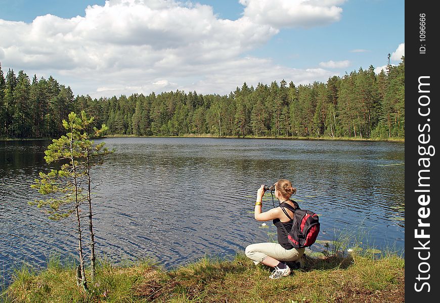 Teenage girl watches to other side of the lake with binocular