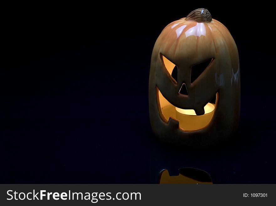 Ceramic pumpkin with tea candle burning on black plexi with type space. Ceramic pumpkin with tea candle burning on black plexi with type space.