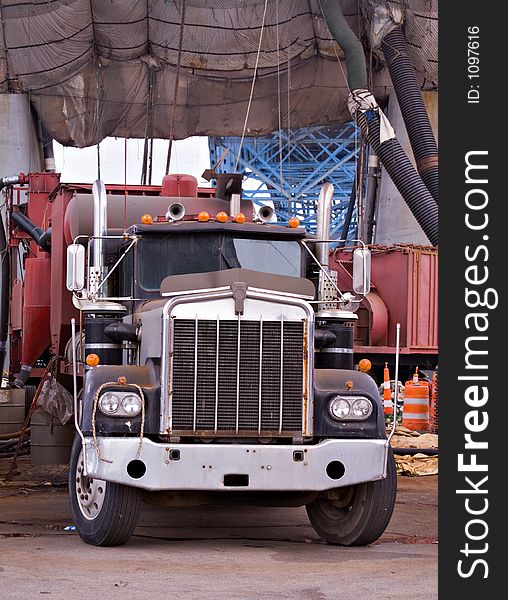 A large  tractor trailer truck working on job site. Painting a very large city bridge overhead and draped. A large  tractor trailer truck working on job site. Painting a very large city bridge overhead and draped.