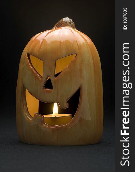 Ceramic pumpkin with tea candle burning on black background. Ceramic pumpkin with tea candle burning on black background.