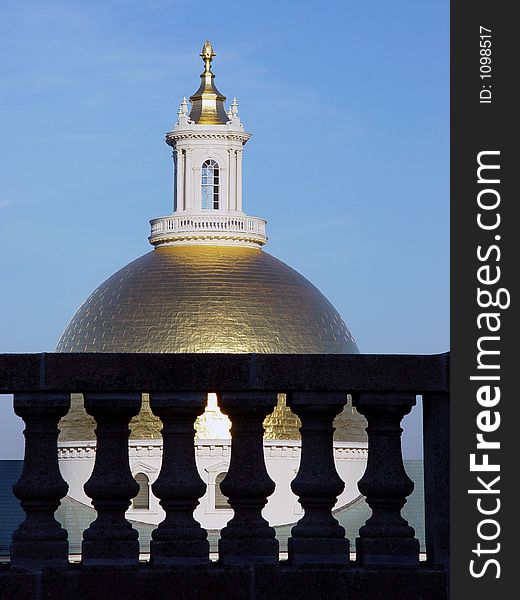 The golden dome of the state house with cement pillars in the foreground, dome is at eye level. The golden dome of the state house with cement pillars in the foreground, dome is at eye level