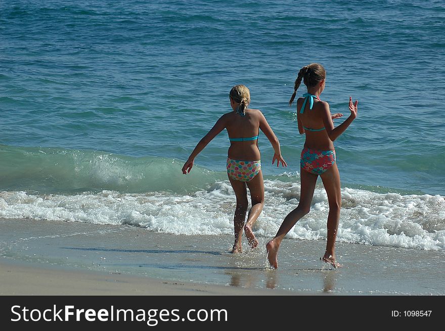 Two teenage girls are running to the water. Two teenage girls are running to the water