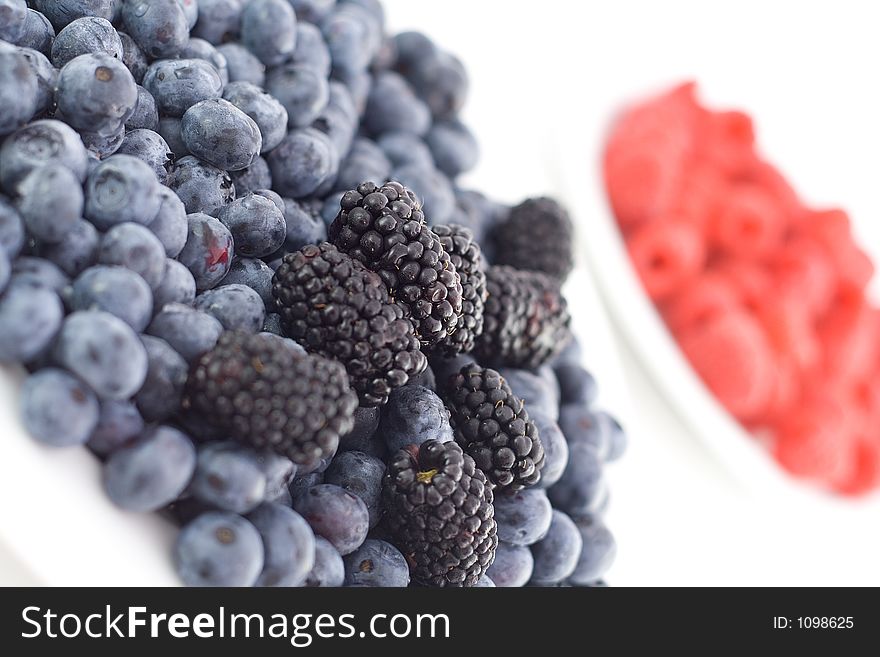 Mixed berries on a plate with raspberries in the background