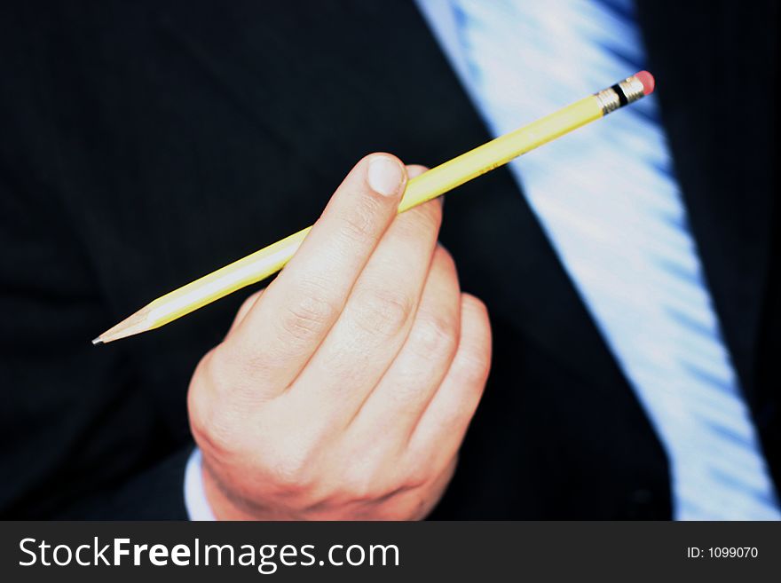 Business man wearing blue tie and blue shirt is holding yellow pencil between his fingers. Business man wearing blue tie and blue shirt is holding yellow pencil between his fingers