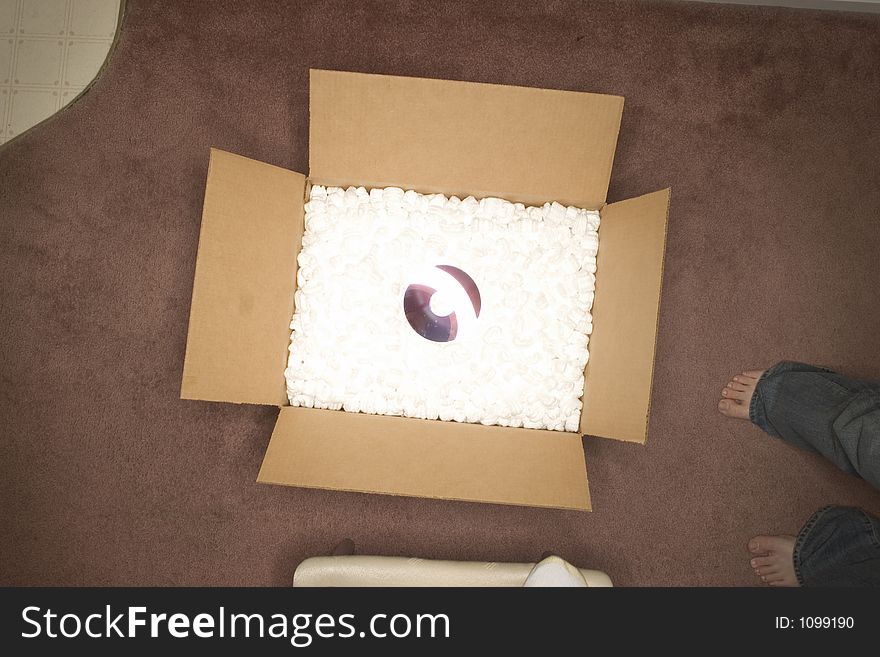 Reflective object in the middle of an open box on pink carpet. Reflective object in the middle of an open box on pink carpet