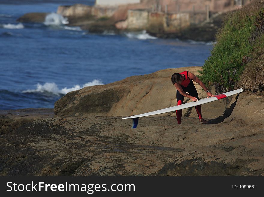 Surfer waxes up on a beautiful morning. Surfer waxes up on a beautiful morning.