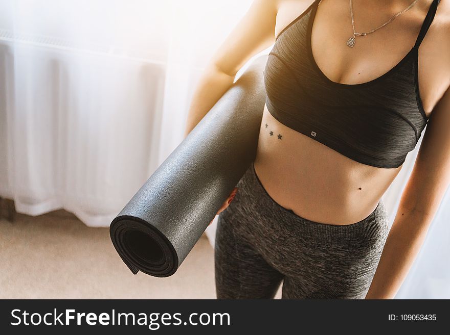 Woman in Black Sports Bra With Grey Leggings Carrying Yoga Mat