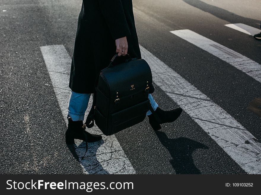 Person Carrying Bag Walking on Pedestrian Lane