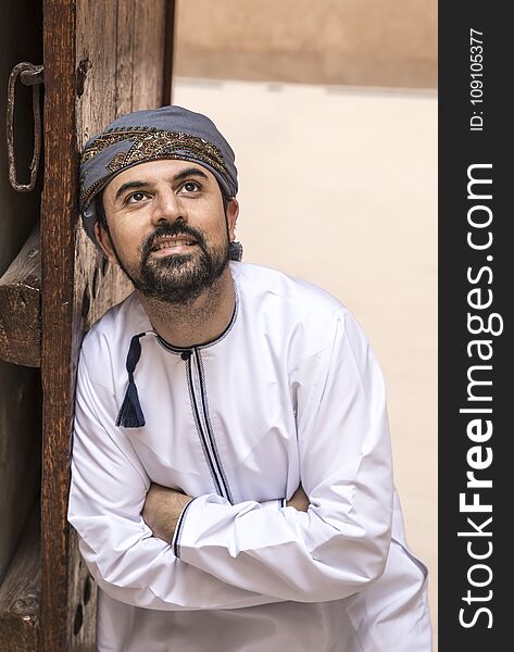 Man in traditional Omani outfit through an old doorway. Man in traditional Omani outfit through an old doorway