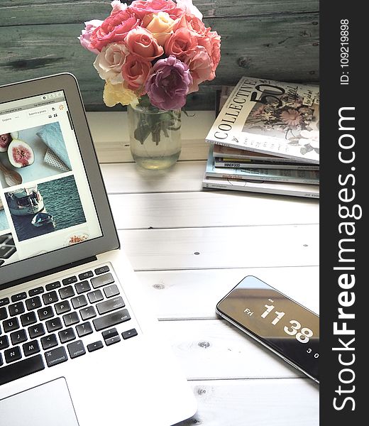 Macbook Air, Flower Bouquet and Magazines on White Table