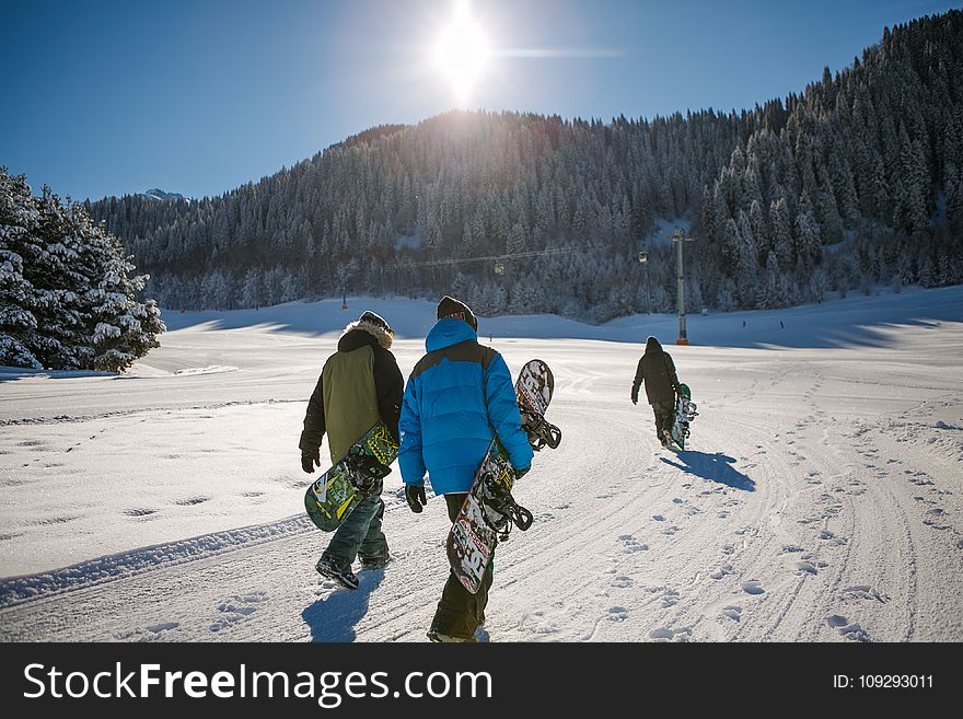 Three Person Holding Bubble Jacket Carrying Snowboards