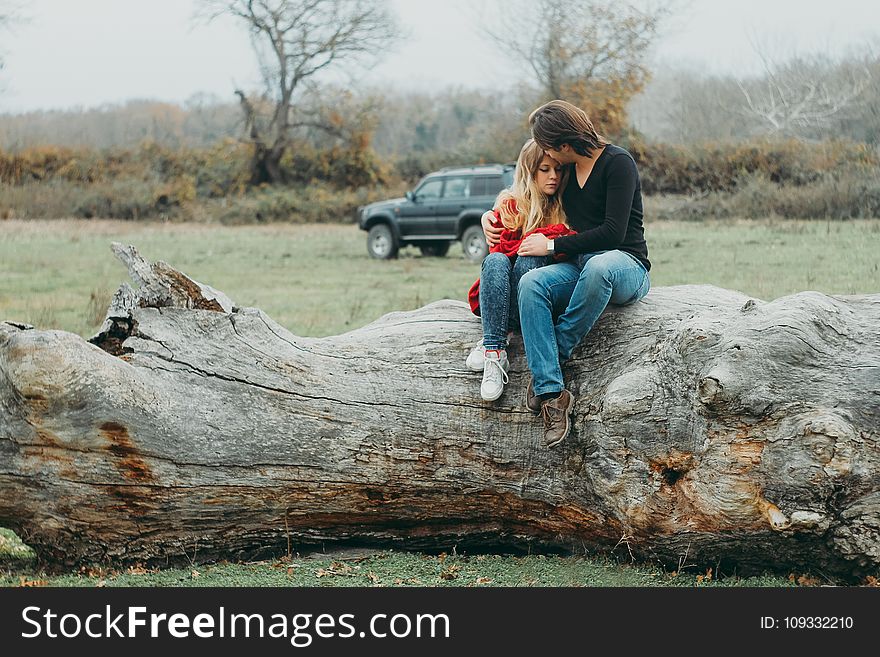 Mother and Daughter Sitting on Tree Log