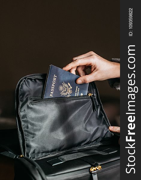 Person Putting a Passport on Bag