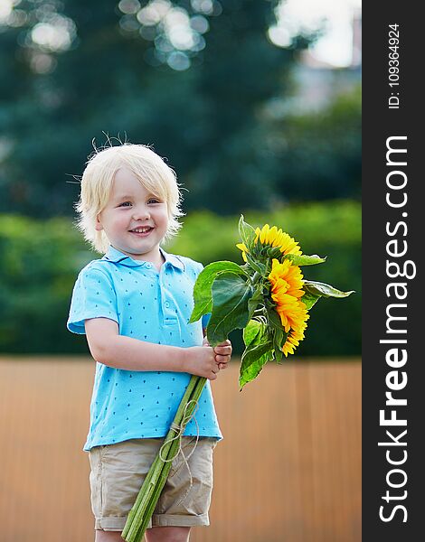 Little boy with bunch of sunflowers outdoors