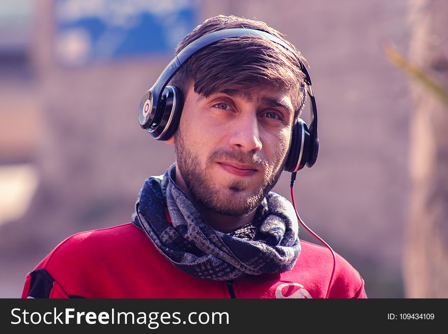 Closeup Photo Of A Man Wearing Red Top, Gray Scarf, And Black Beats By Dr. Dre Headphones