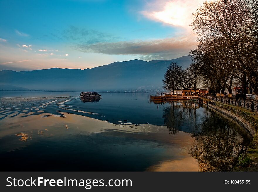 Sunset over Ioannina city and lake Pamvotis. seafront street for cars,pedestrians and bicycles .Epirus, Greece.