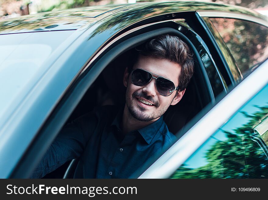 Take your seat! Handsome young man looking at camera with smile while sitting in car. Take your seat! Handsome young man looking at camera with smile while sitting in car