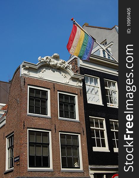The international gay rainbow flag with old Amsterdam houses. The international gay rainbow flag with old Amsterdam houses