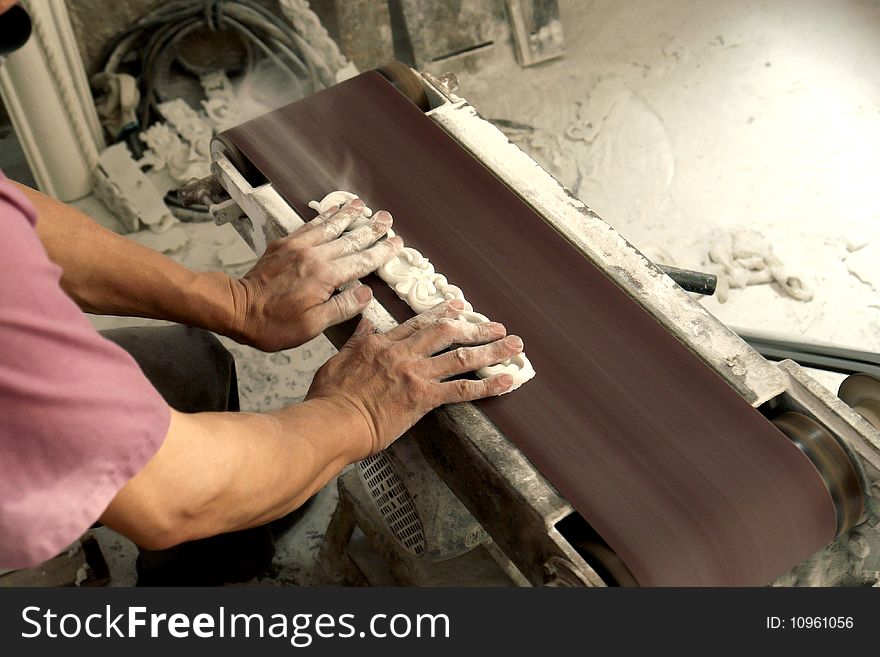 In workshop,a man use smoothing machine to make a lace border for construction deco material market. In workshop,a man use smoothing machine to make a lace border for construction deco material market.