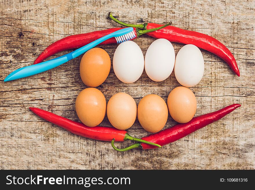 Eggs and red pepper in the form of a mouth with teeth. White eggs are bleached teeth. Yellow eggs - before bleaching. Teeth whitening before and after.