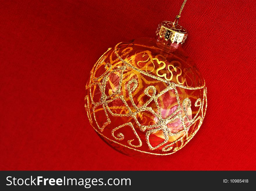 A close up of a glass gold painted bauble against red background. A close up of a glass gold painted bauble against red background
