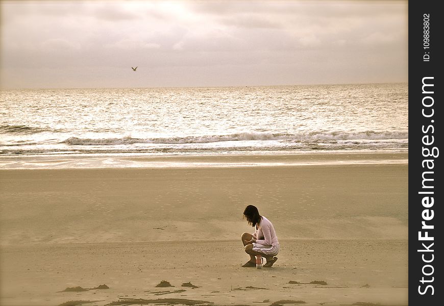 Woman in Pink Cardigan Sitting on Seashore