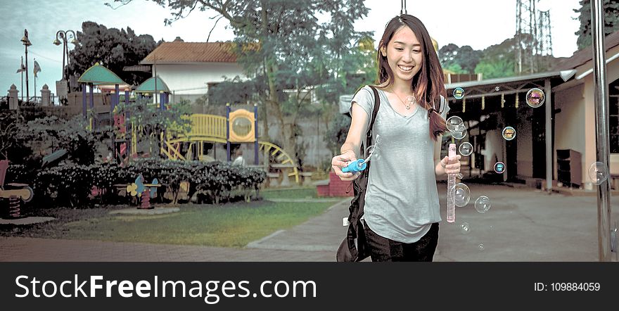 Woman Wearing Gray V Neck Cap Sleeve Top Making Bubbles