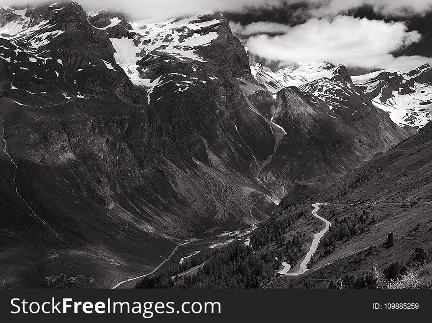 Greyscale Photo of Mountains Surrounded by Clouds