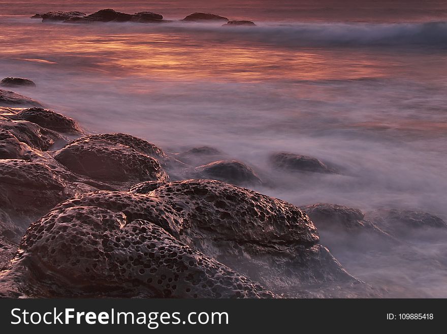 Brown and Black Rock Formations With Fog during Sunset