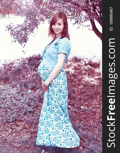 Woman In Blue Maternity Coat And White And Blue Floral Maternity Dress