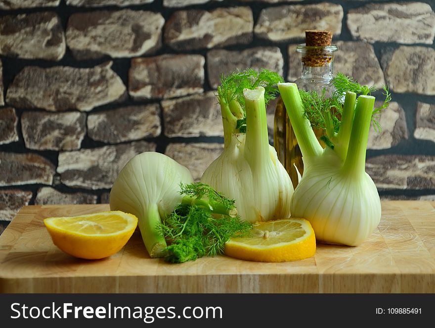 Green and White Onions and Sliced Lemons on a Brown Surface