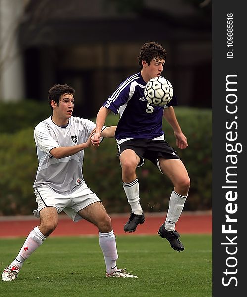 Two Men Playing Soccer At Soccer Field Near Green Plants During Daytime