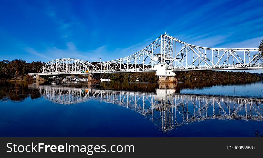 White Bridge Above Body of Water Creating a Reflection Under White Clouds