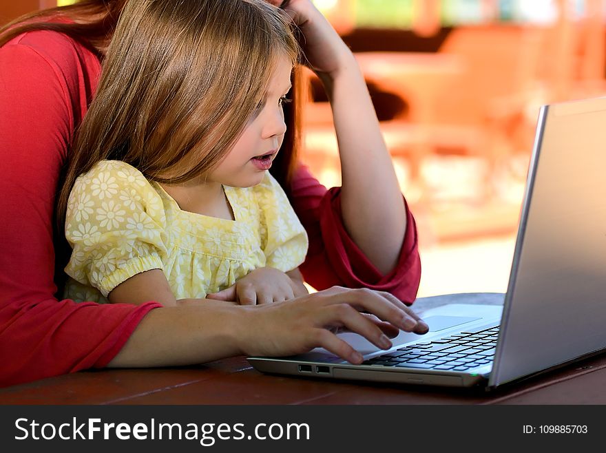 Brunette Woman in Red With Girl in Yellow on Lap Before Laptop