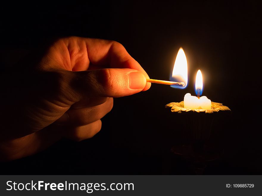 Person Holding Match Stick With Fire in Front of Candle With Fire