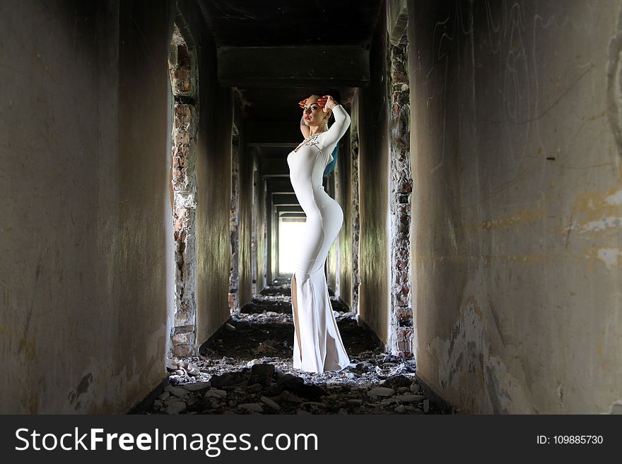 Woman in White Bodycon Maxi Dress Posting in Between White Concrete Wall