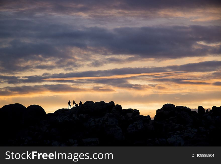 Silhouette Of 4 Persons Resting On Top On Mountain During Dusk