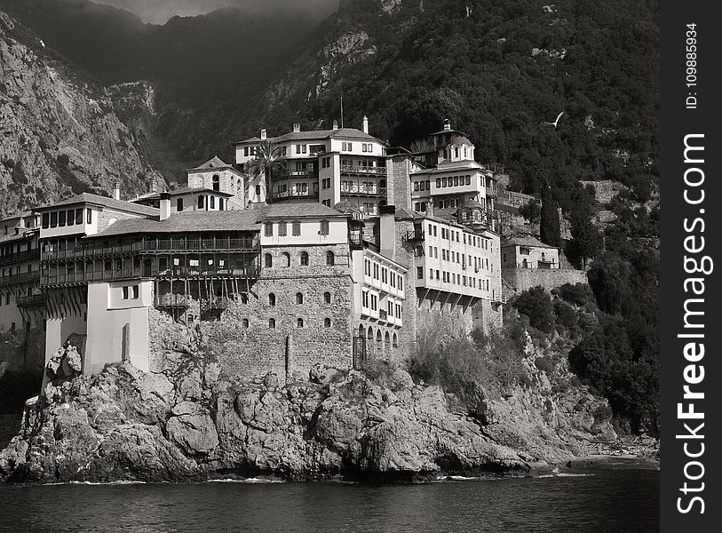 Landscape Photography of Gray and White House Near Mountain Cliffs Above Body of Water