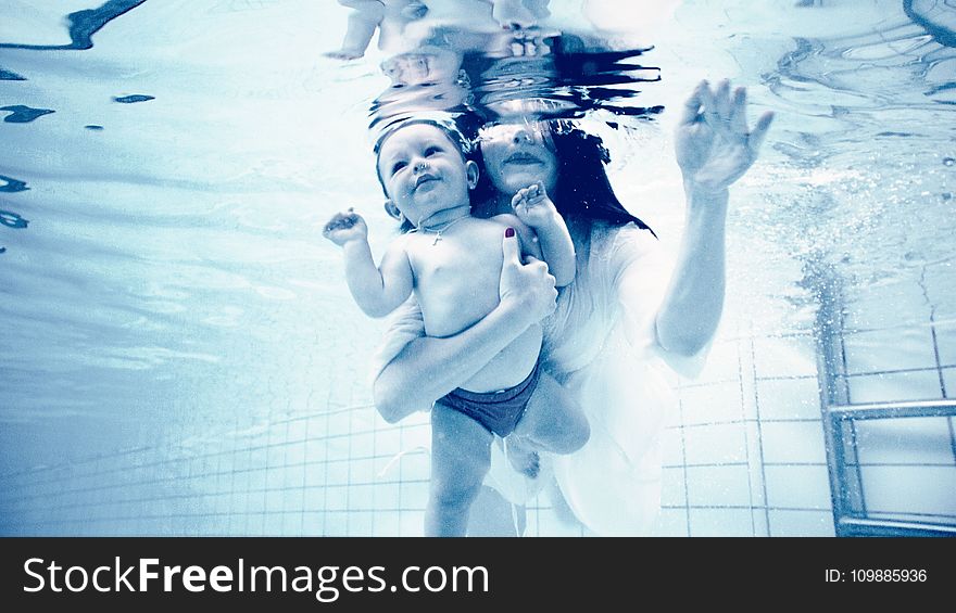 Grayscale Photography Of Woman Holding Baby In Swimming Pool