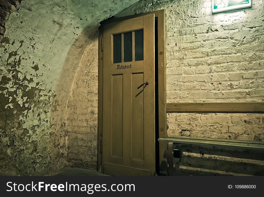 Brown Wooden Door Near White Brick Wall