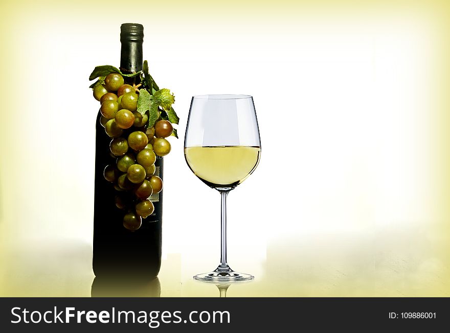 Wine In Wine Glass Near Green Glass Bottle