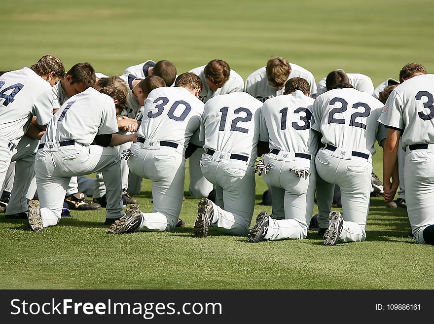 Baseball Player Kneeling on Grass Field during Daytime