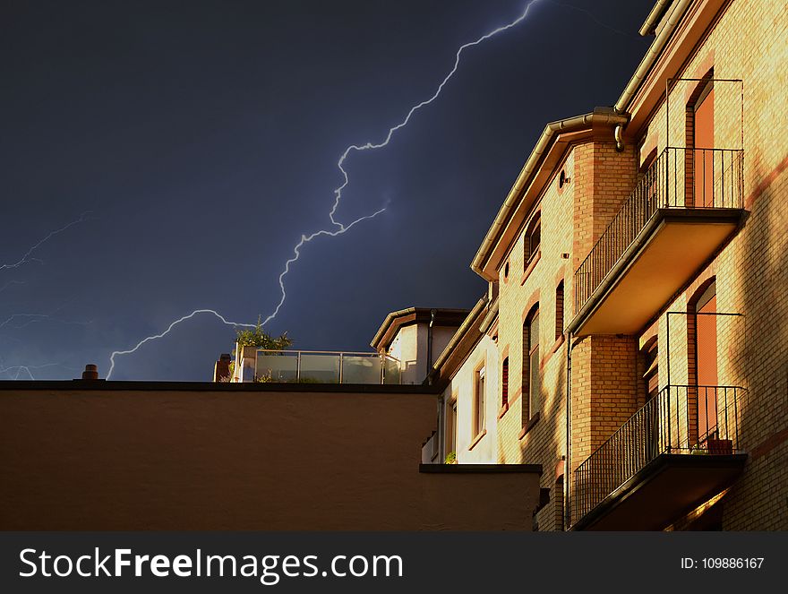 Yellow Building Under Thunderstorm in Black Sky