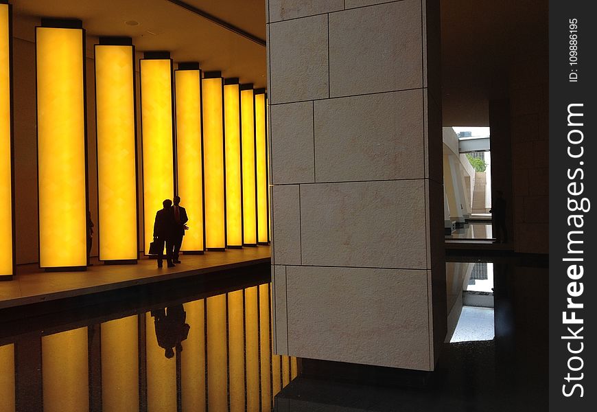 Silhouette Photo Of 2 Person Beside Beige Concrete Lighted Wall